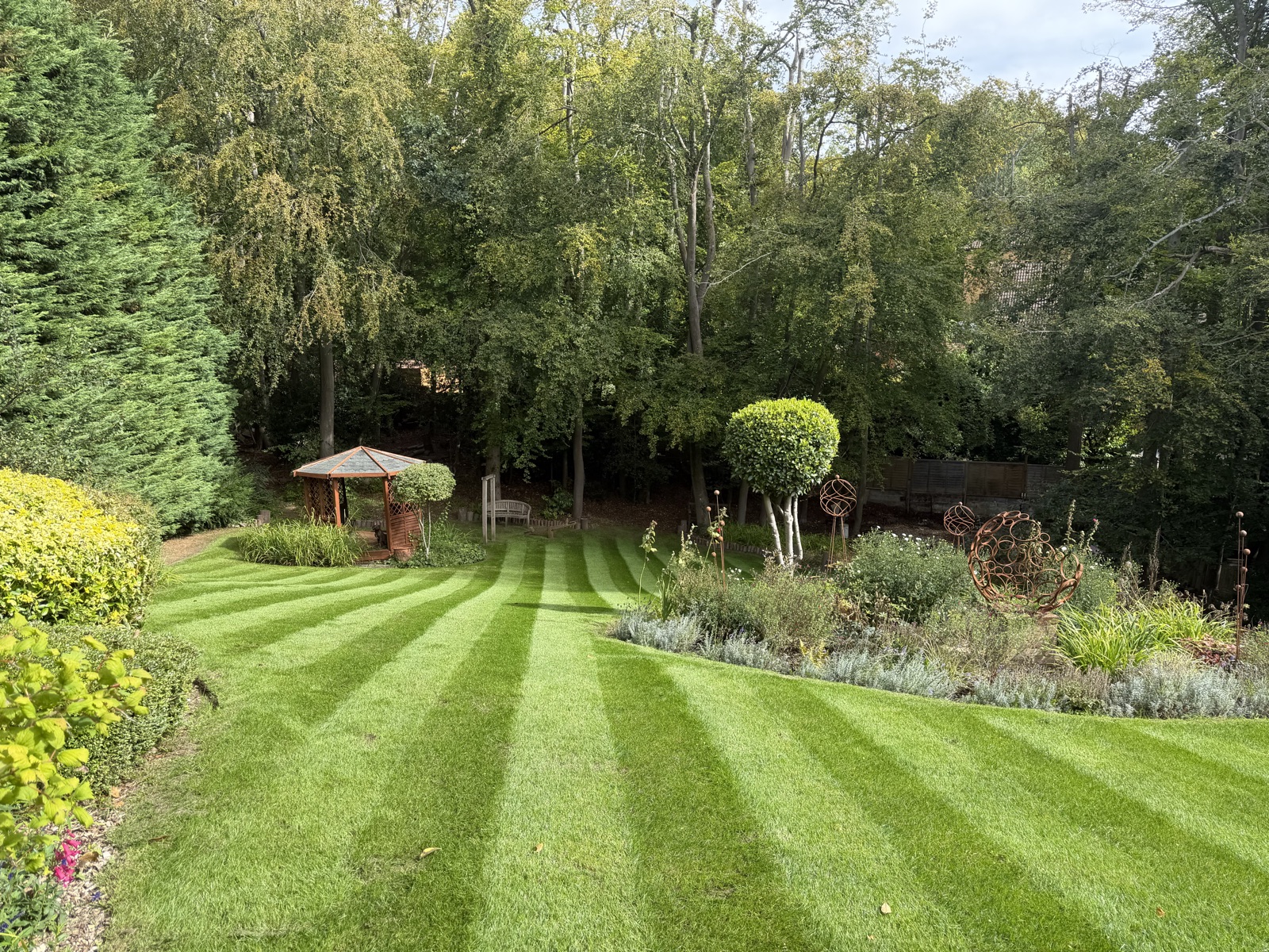 Striped lawn with gazebo and garden sculptures